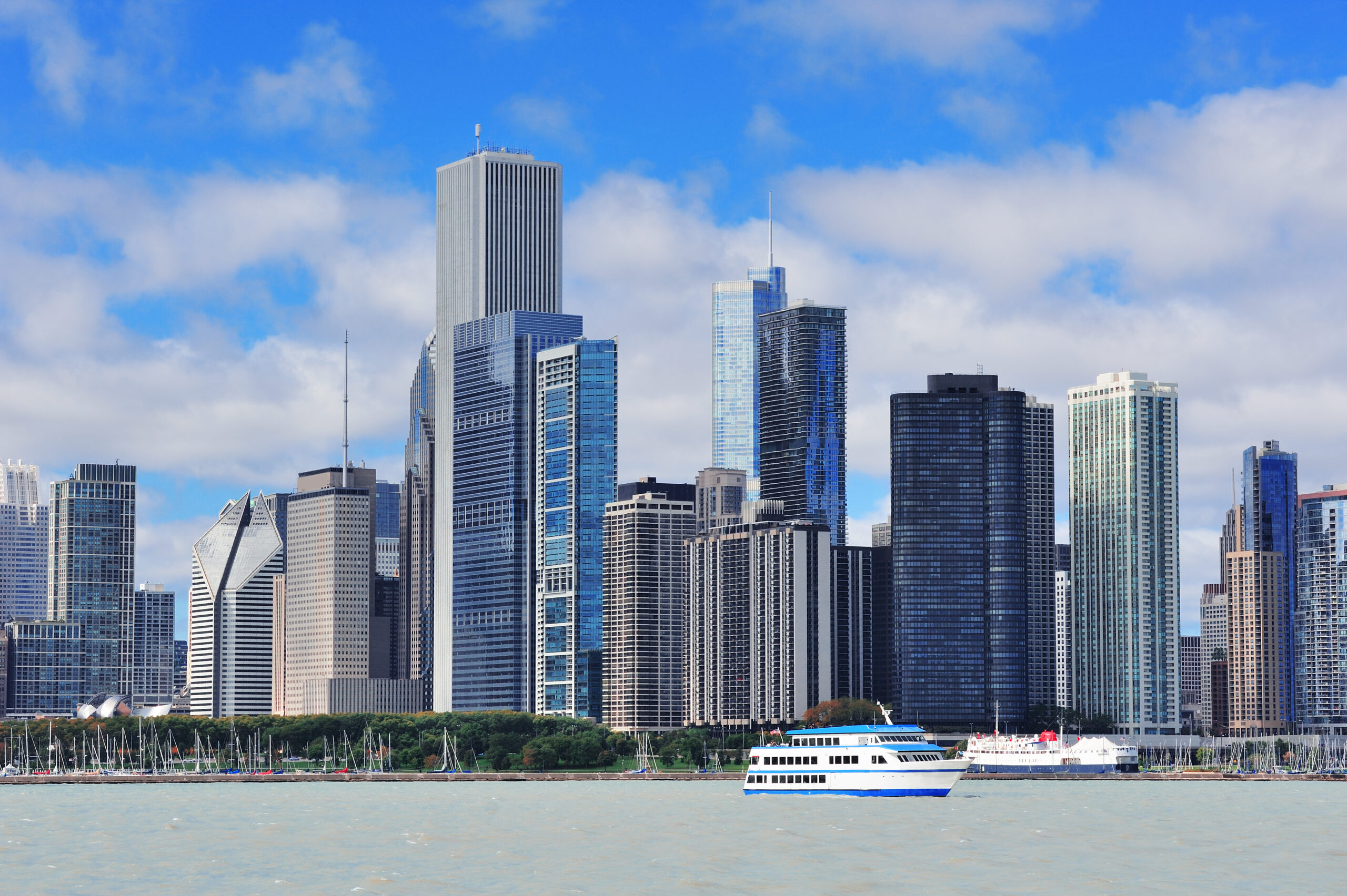 Chicago city urban skyline with skyscrapers over Lake Michigan with cloudy blue sky.