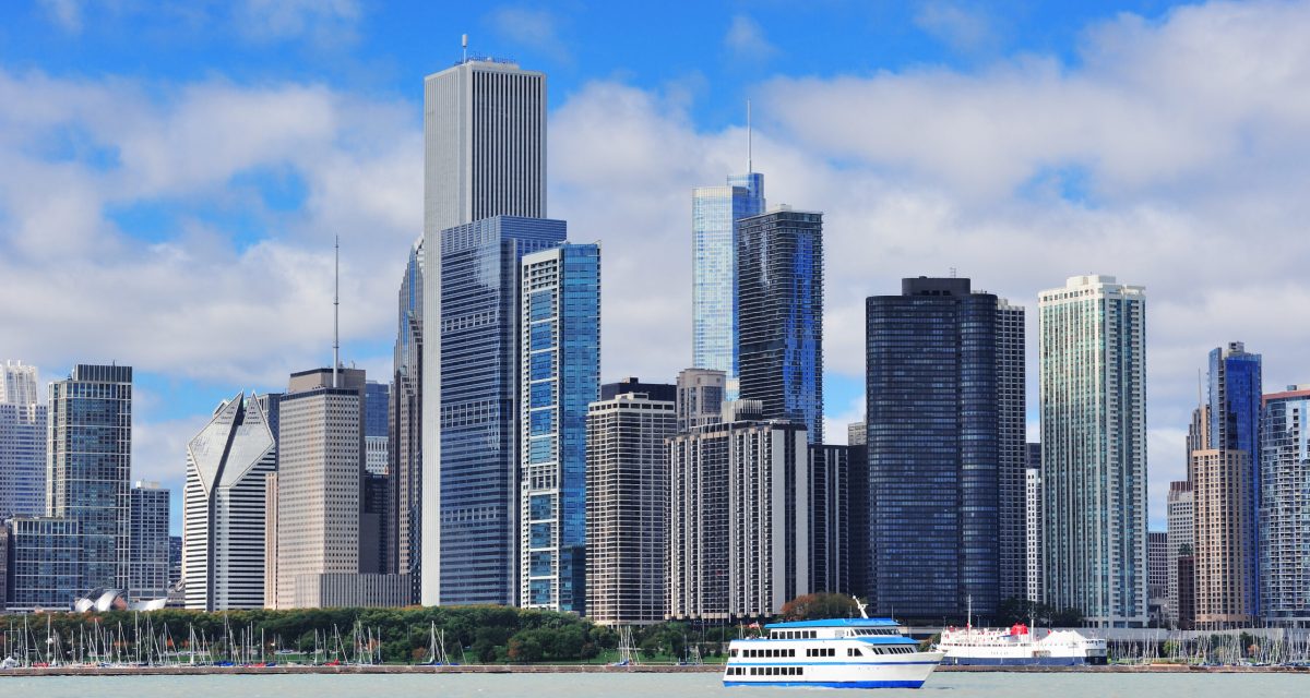 Chicago city urban skyline with skyscrapers over Lake Michigan with cloudy blue sky.